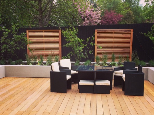 4 black chairs around a black table, in a newly renovated garden with wooden floors